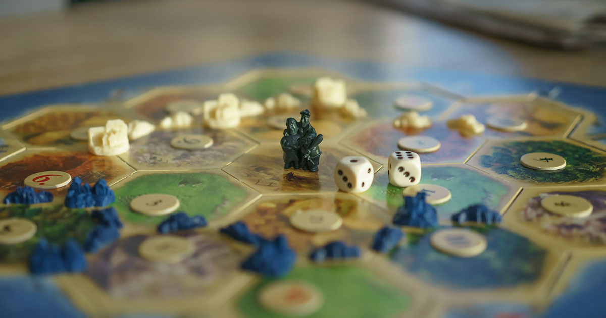 Catan strategi: närbild på spelpjäser och resurskort
